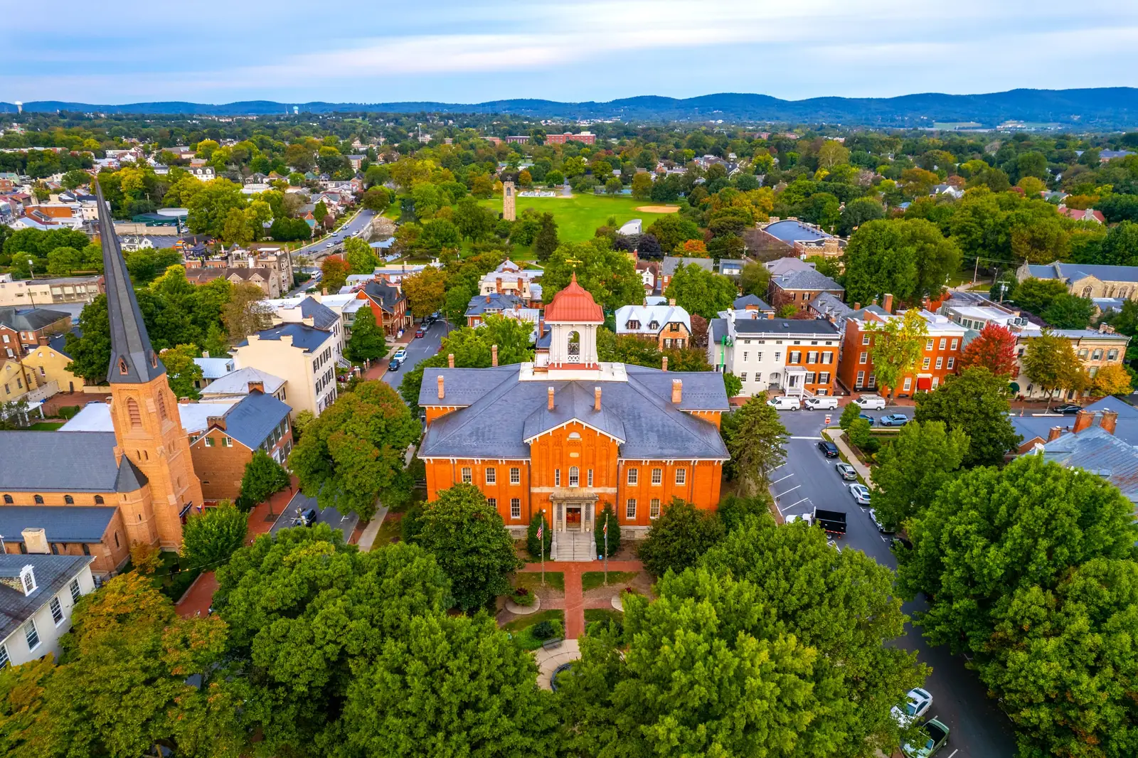 Downtown Frederick from above in early autumn: City Hall's red cupola, a church spire and brick rowhouses, with Catoctin Mountain on the horizon